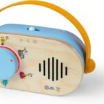 A close-up of the Baby Einstein + Hape Discovery Radio Toy, a small wooden radio with a dial and flexible strap.