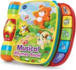 A red VTech Musical Rhymes Book, open to a colorful page with interactive elements and piano keys.